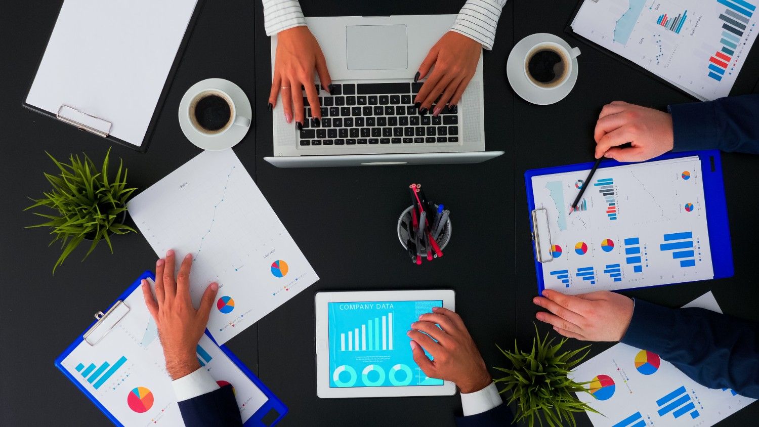Corporate manager explaining what to outsource to businesspeople, meeting shot from top view in a company office. Working in team conferences with project planning documents on the table.