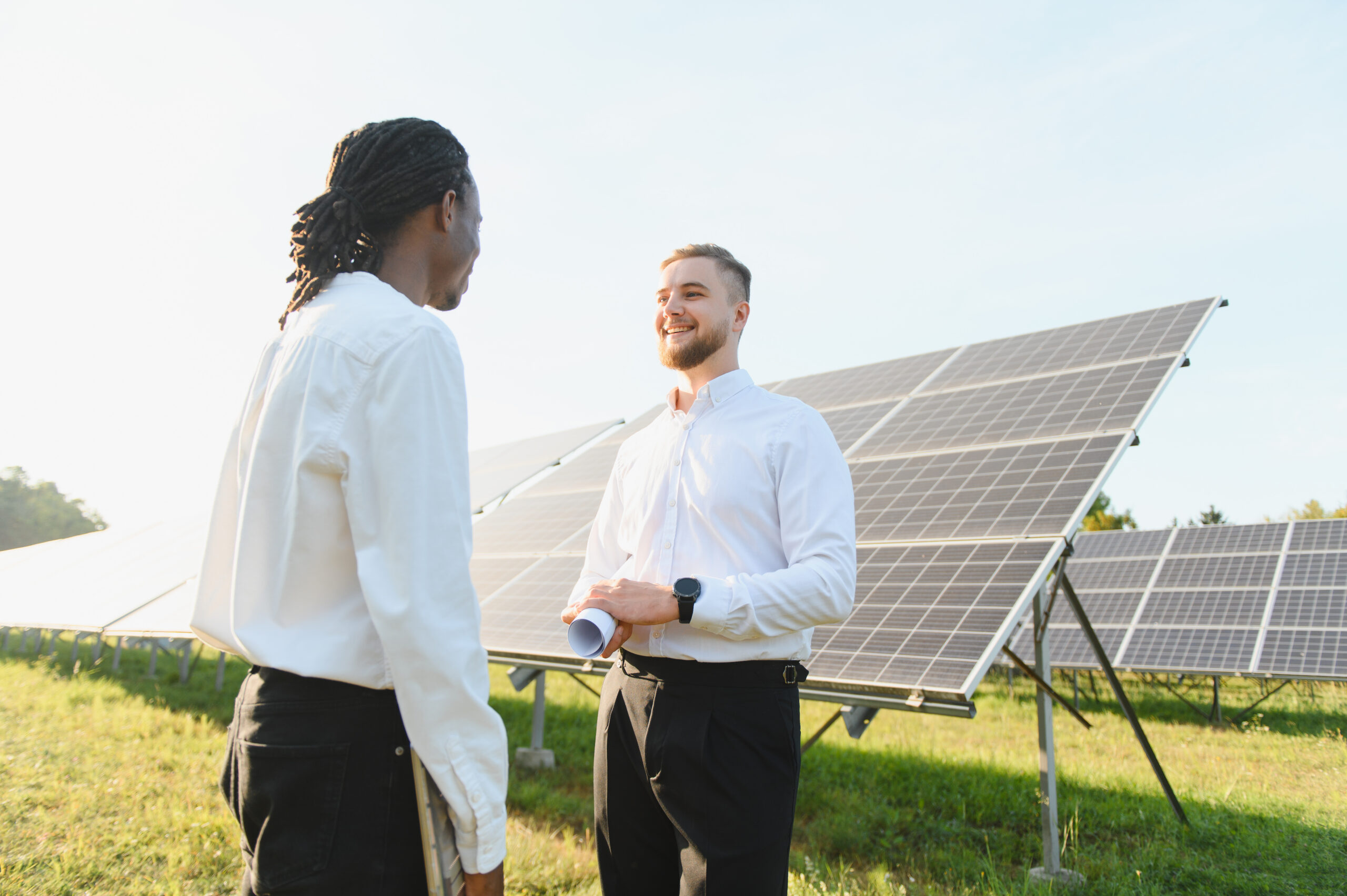 Solar energy experts in discussion with solar panels in the background.