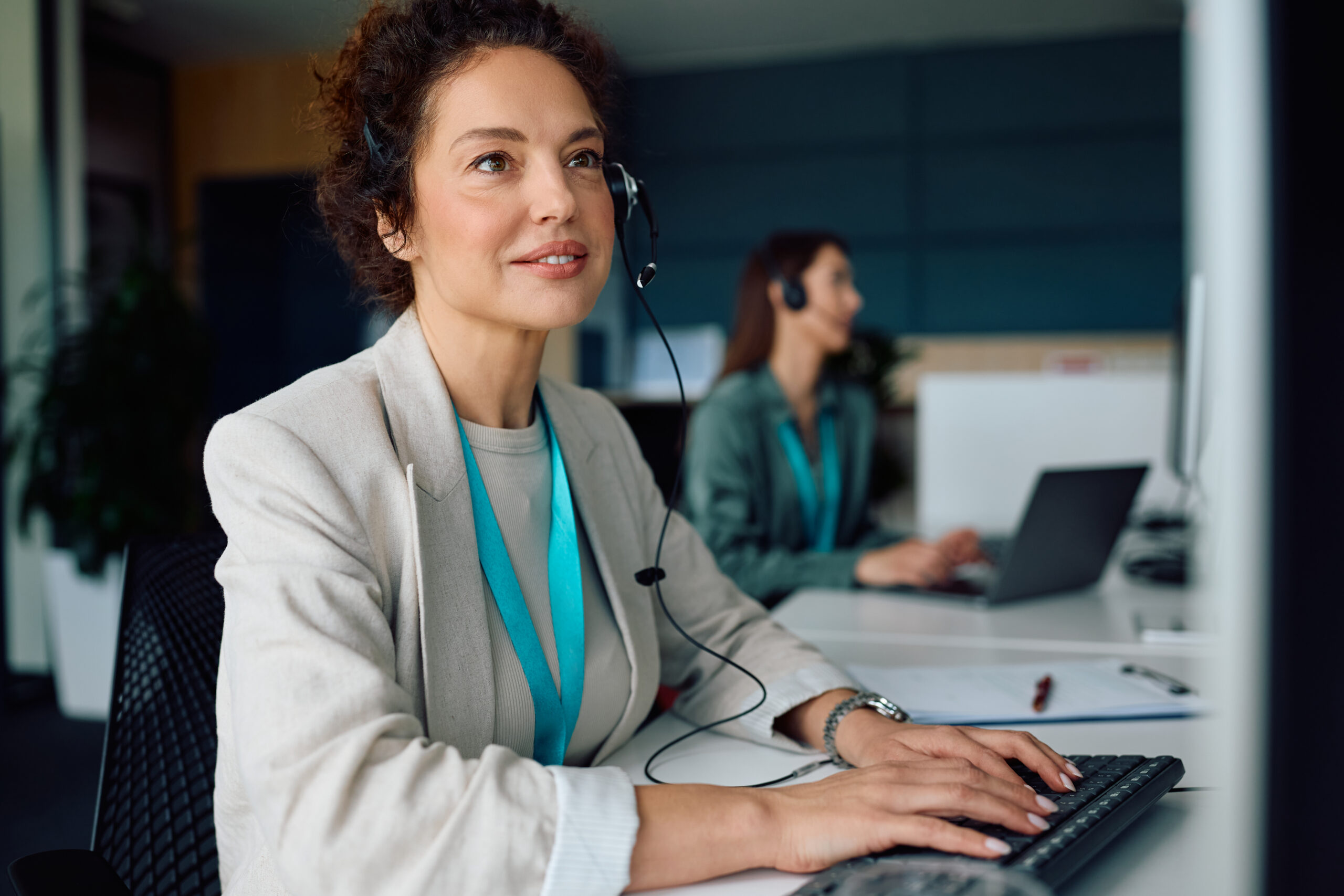 Smiling call center agent using computer while working in the office.