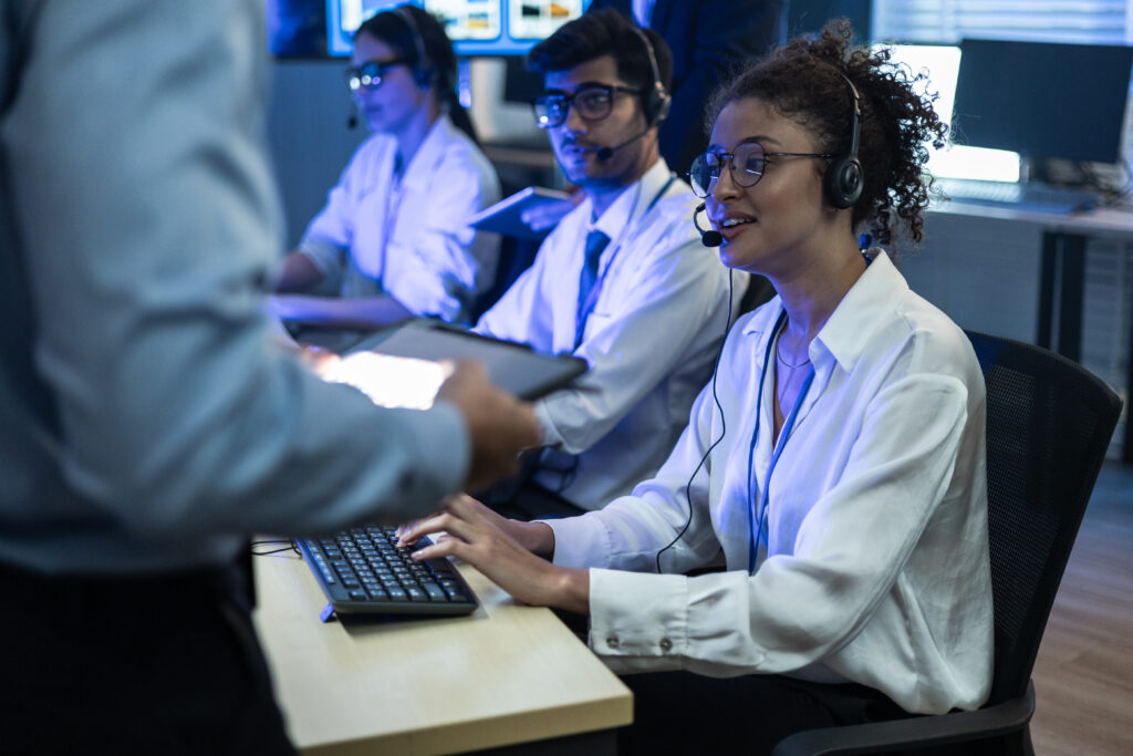 Diverse team of customer support agents with headsets working in a high-tech call center. Professional telemarketers providing online assistance and technical service at the office.