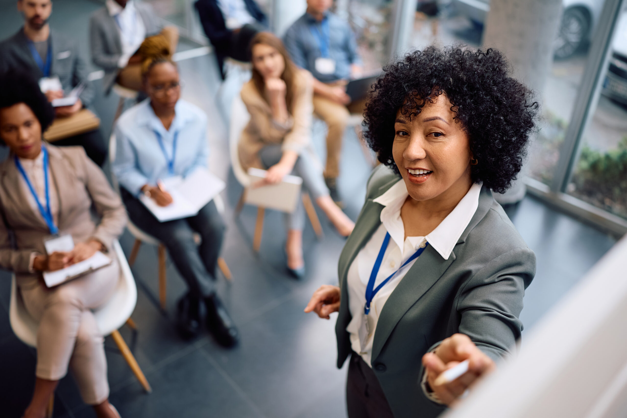 Female CEO giving a presentation in front of whiteboard during business seminar at conference hall.