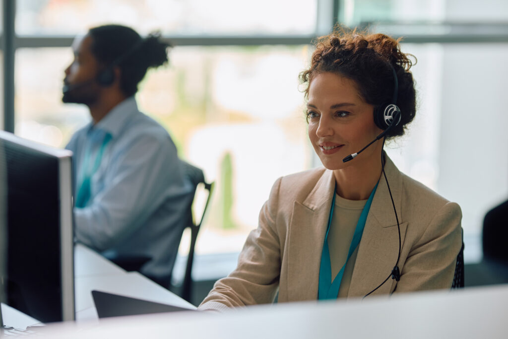 Smiling businesswoman working on desktop PC in the office at call center.